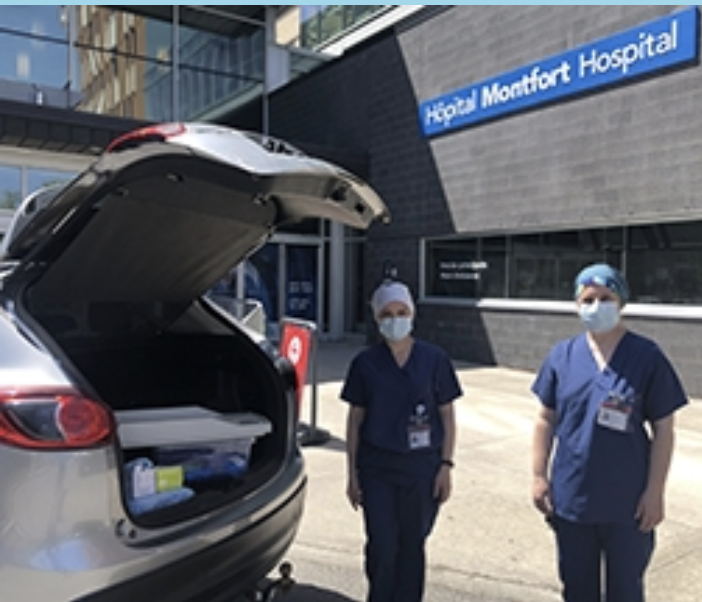 Deux professionnels de la santé portant un masque posant devant l'hôpital