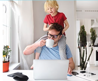 Homme devant sont portable et tenant son enfant sur ses épaules.