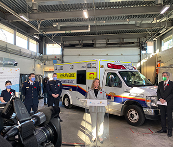 Groupe de dignitaires dans un garage devant une ambulance