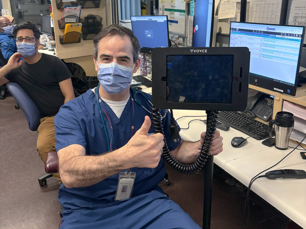 Professionnel de la santé masqué qui pointe vers un appareil d'interprétation "Voyce"